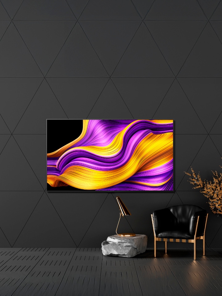 ภาพทีวี OLED ที่วางในห้องตกแต่งโทนโมโนโครม ติดบนกำแพงข้างเก้าอี้หุ้มเบาะสีดำ