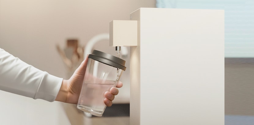 A woman using LG water purifier to get a cup of water.