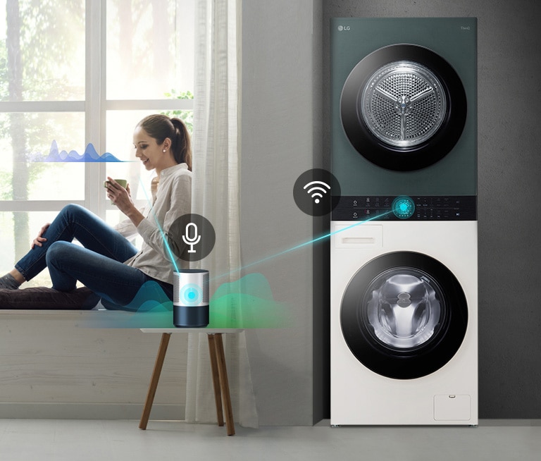 ผู้หญิงนั่งอยู่ริมหน้าต่างถือถ้วยกาแฟข้างเครื่องซักผ้า LG และลำโพงเสียงอัจฉริยะ.