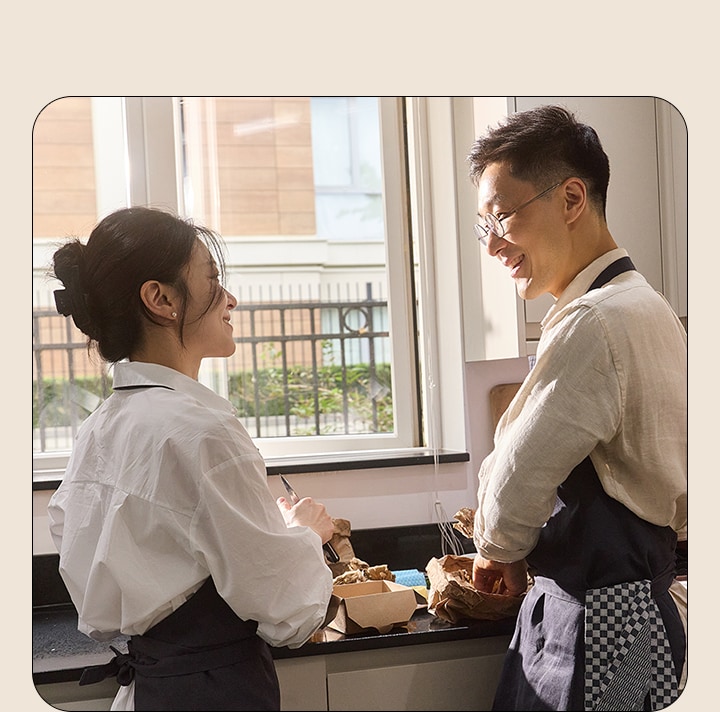 ชายและหญิงกำลังมองตากันขณะทำอาหารอยู่ในห้องครัว