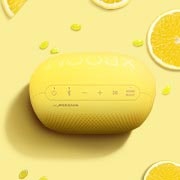 Sarı bir fonun üzerine limonlar, Jellybean'ler ve LG XBOOM Go PL2S yerleştirilmiştir.