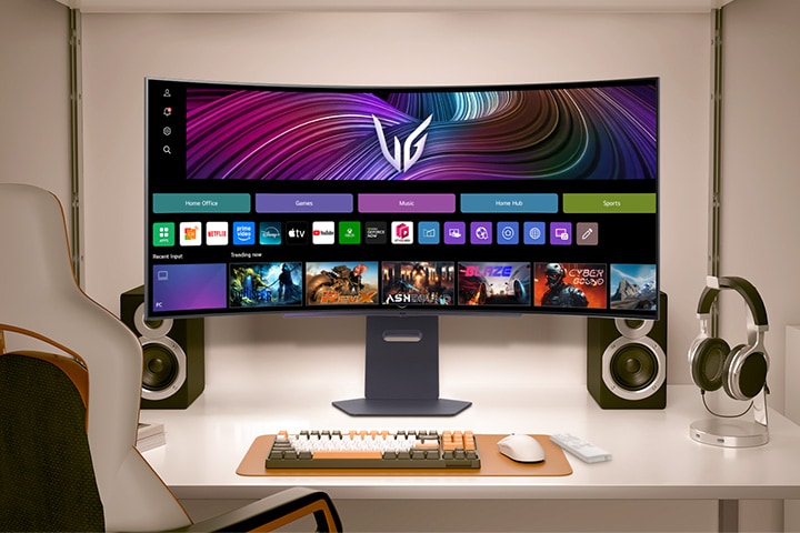 Video, masadaki öne bakan bir monitörü gösteriyor ve webOS görüntüleriyle oyun sahneleri arasında geçiş yapıyor.