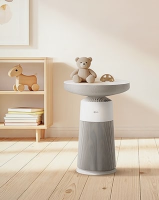 LG Aerospeaker 在兒童房間的圖片，放在木架旁，用作邊桌，桌上放著泰迪熊公仔和玩具。	
