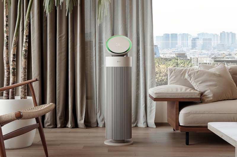 LG 空氣清淨機放置在配有米色沙發、深色書架和現代風格裝飾的客廳中