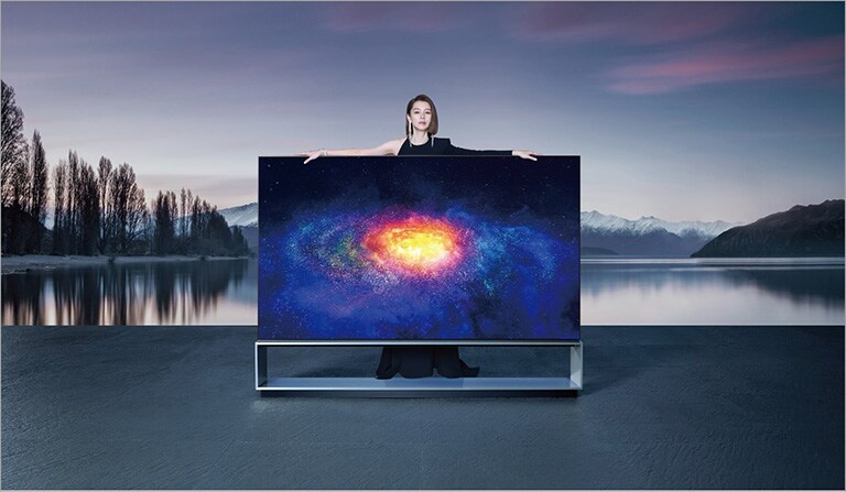Vivian站立於Oled 8k電視後方，張開手臂倚靠在電視上方
