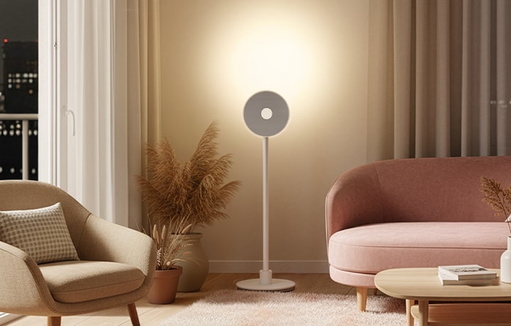 LG MoodMate 置於現代風格客廳空間 於夜晚時分，搭配曲線沙發與單椅，營造溫潤且沉靜的氛圍。