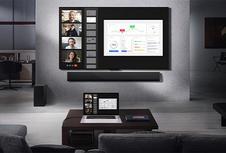 客廳的沙發上可以看到風景，對面是壁掛式 LG True Wireless 電視和 LG Soundbar。咖啡桌上有一台筆記型電腦，它連接到桌子下方幾乎看不見的零連接盒。具有即時視訊通話功能的筆記型電腦螢幕可以無線鏡像到電視螢幕上。整個空間整潔，沒有電線雜亂。
