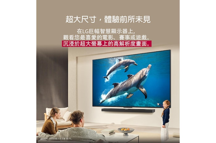一家人坐在沙發上，面對 LG Soundbar 上方的壁掛式 LG QNED TV，一個小女孩指著螢幕，螢幕上顯示著兩隻海豚。標題說明巨大的螢幕上每個動作都更加震撼人心。
