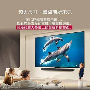 一家人坐在沙發上，面對 LG Soundbar 上方的壁掛式 LG QNED TV，一個小女孩指著螢幕，螢幕上顯示著兩隻海豚。標題說明巨大的螢幕上每個動作都更加震撼人心。