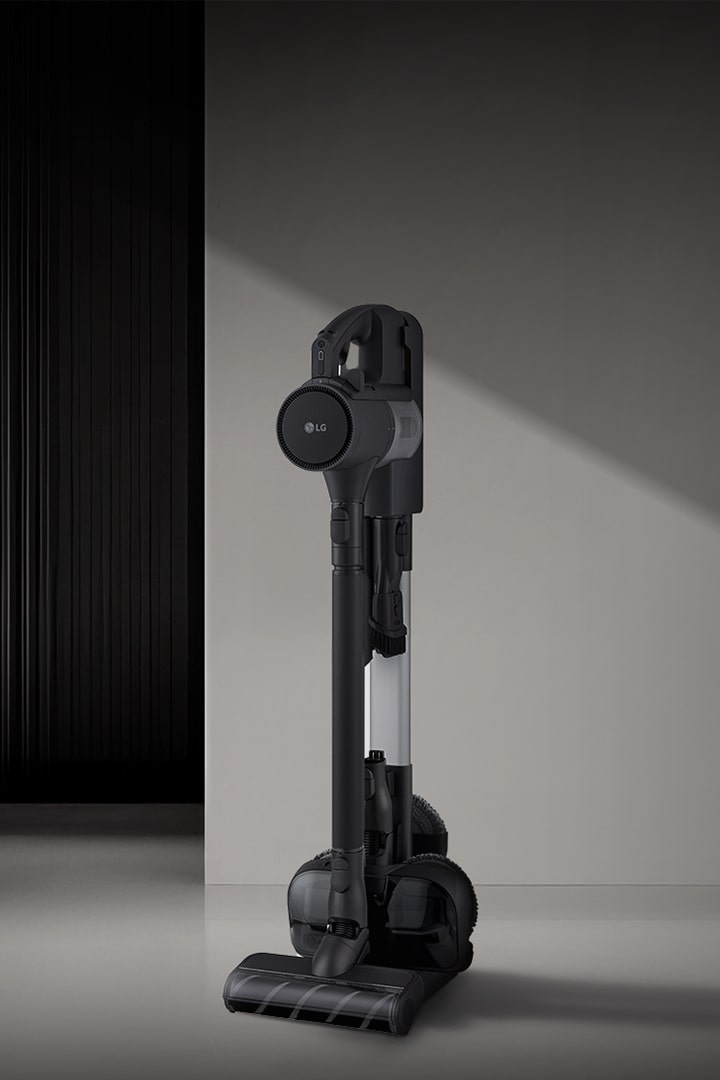  LG a9k-legend3 吸塵器直立放置在簡約的深色地板上，並以現代風格背景照明。