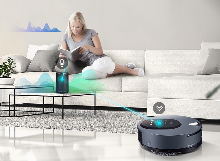 Three icons at the top indicate there are three images in a carousel. The first icon, labelled "Voice Control", is red. A woman sits on a couch reading in the background as the machine is in the foreground. A blue line is drawn between the machine and an AI speaker that has listened to the woman and is directing the mop. Wave lines are drawn near the woman to indicate speaking and near the AI speaker to indicate directing the machine.