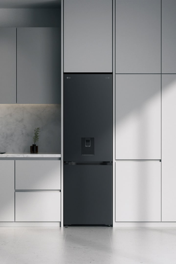 LG bottom freezer (GBFSJ10DEP) in matte black with water dispenser built into grey cabinets beside a marble island and window