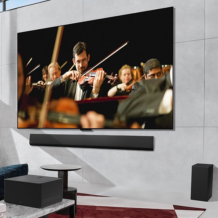 An LG OLED TV playing orchestra on the screen mounted flat against a wall and a Zero Connect Box placed in front.