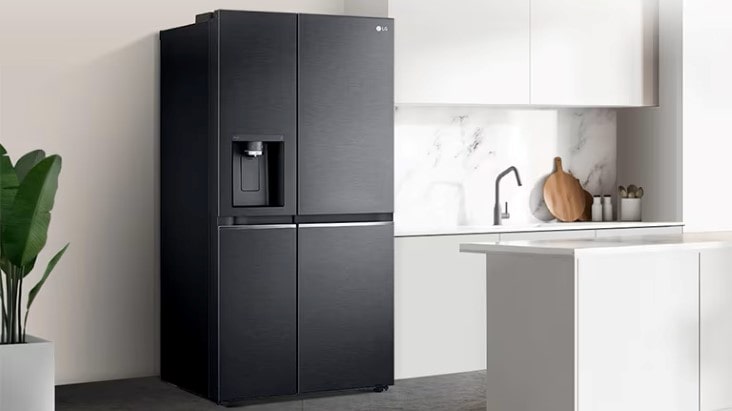 Black LG American style fridge freezer with water dispenser, shown in a modern white kitchen with marble backsplash and island counter.