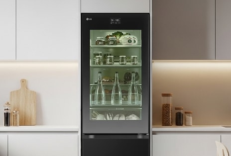 LG tall fridge freezer with InstaView glass panel, showcasing neatly organised contents in a minimalist white kitchen with under-cabinet lighting.