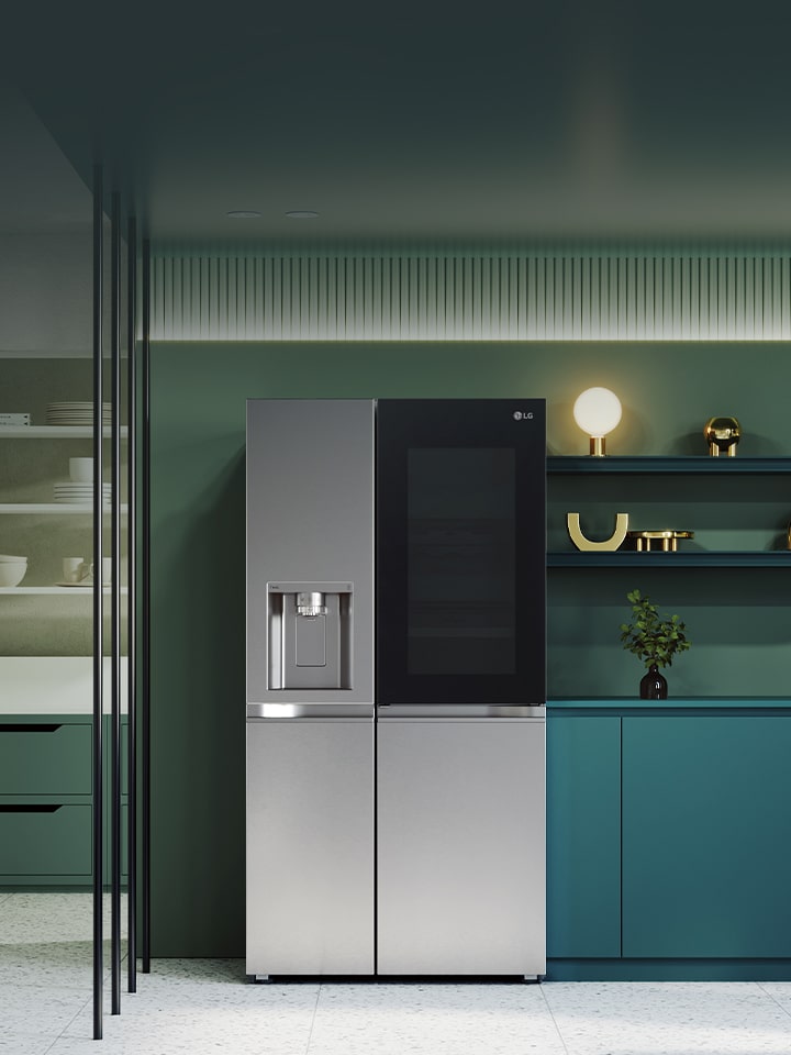 LG InstaView fridge freezer centered in a green kitchen with surrounding shelves sink and built-in appliances