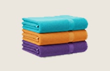 Stack of folded towels in orange, green, and purple.	