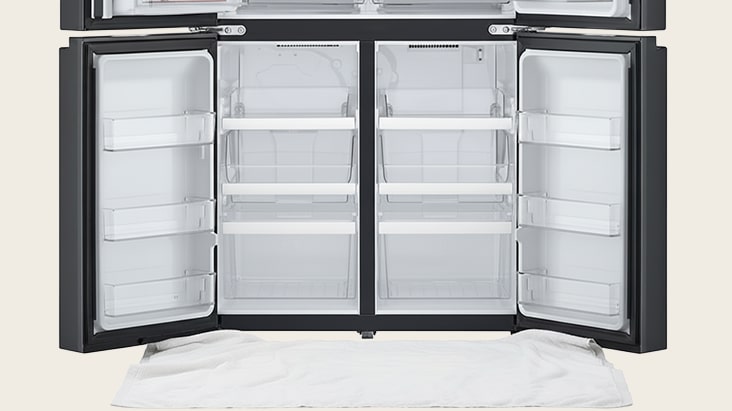 LG refrigerator with both doors open and a white towel placed underneath to catch any dripping water during defrosting.