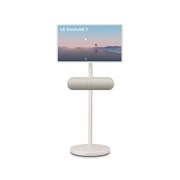 LG StanbyME 2 screens displayed in a modern living room. There is a StanbyME 2 on a stand, one is hung on the wall, and the other is propped up on a table using the folio cover.