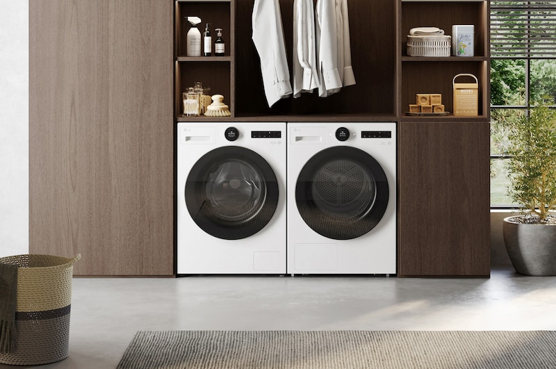 A lifestyle image showing the white LG RHX7010TWB 10kg DUAL Inverter Heat Pump Dryer beside a matching washer in a cozy, earth‑toned setting.