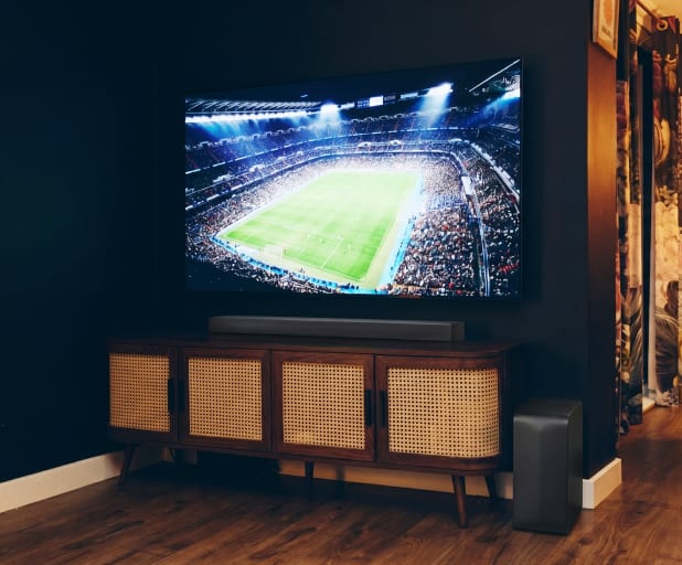 Close-up of a soundbar below a TV on a wooden cabinet