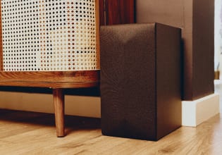 Wireless subwoofer placed next to a wooden cabinet in a living room