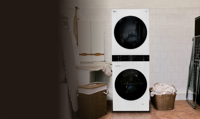 White LG stacked washer and dryer with black circular doors in a tiled laundry room, surrounded by wicker laundry baskets, a cabinet, and hanging clothes.