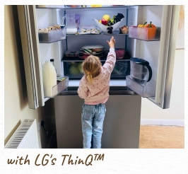 A toddler reaches inside an open, lit refrigerator. [with LG's ThinQ™]