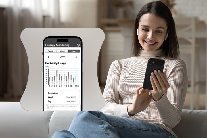 A woman smiles while looking at her smartphone in the living room, with the LG ThinQ energy monitoring screen displayed on the left.