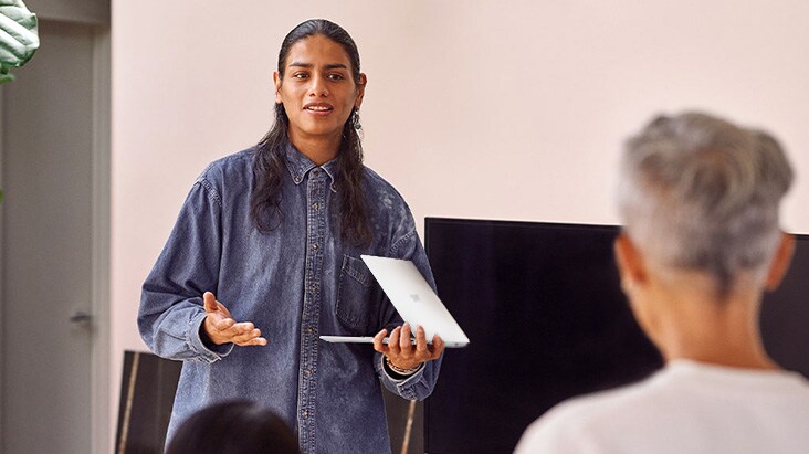 A man is explaining in front of an  audience while holding LG gram.	
