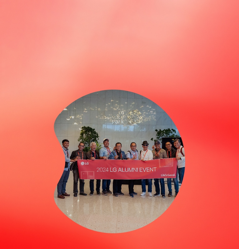 Group of people holding a banner that reads '2024 LG Alumni Event' in front of the LG Science Park. 	