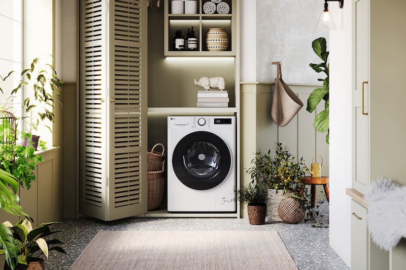 The white LG 13kg washing machine F4Y513WWLN1, featuring a distinctive black porthole ring, shown installed in a stylish, modern laundry closet.