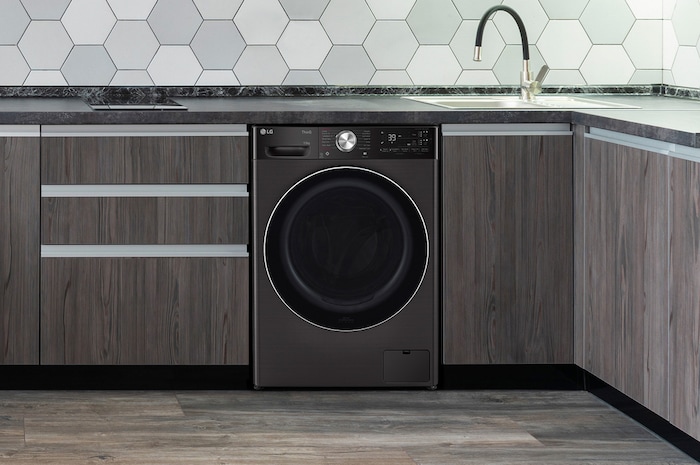 The Platinum Black LG 13kg washing machine F4Y913BCTA1, shown neatly installed under a counter in a modern kitchen.