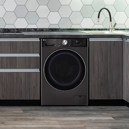 The Platinum Black LG 13kg washing machine F4Y913BCTA1, shown neatly installed under a counter in a modern kitchen.