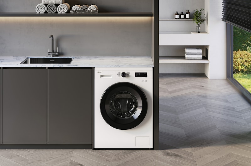 The LG 9kg washing machine F4X1008NWK in Essence White, shown built-under a counter in a modern laundry room.