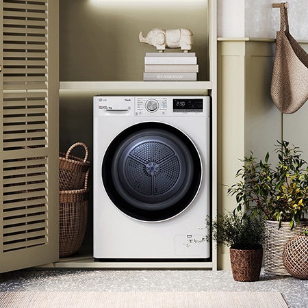 The white LG 9kg dryer FDV709W, featuring a distinctive black porthole ring, shown installed in a stylish, modern laundry closet.