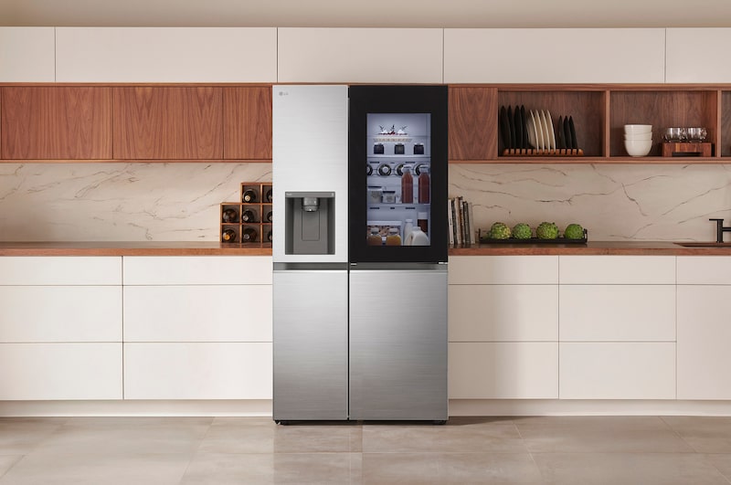 LG Side-by-Side Refrigerator GSXV80PZLE in a stainless steel finish, featuring InstaView™ Door-in-Door® and a dispenser, seamlessly integrated into a modern kitchen with white and wood cabinets.