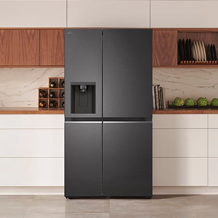 LG Side-by-Side Refrigerator GSLV71MCTD in a matte black steel finish, seamlessly integrated into a modern kitchen with white and wood cabinets, featuring an external water dispenser.