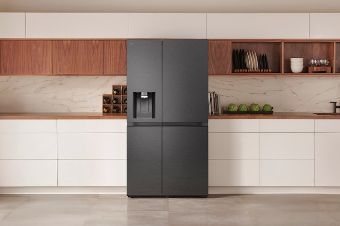 LG Side-by-Side Refrigerator GSLE81EPBD in a matte black steel finish, seamlessly integrated into a modern kitchen with white and wood cabinets, featuring an external water dispenser.