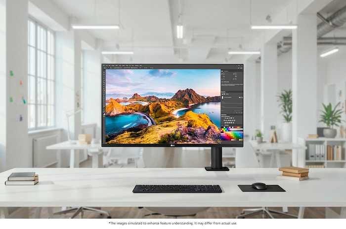 LG Monitor 32UN880K in a dark finish positioned at the center of a bright open-office setup on a white desk, displaying photo editing software for efficient professional work.