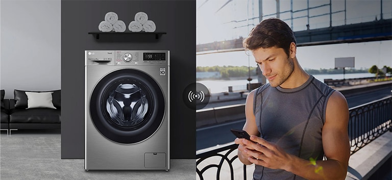 A man outdoors is checking the condition of a washing machine at home through a mobile phone app.