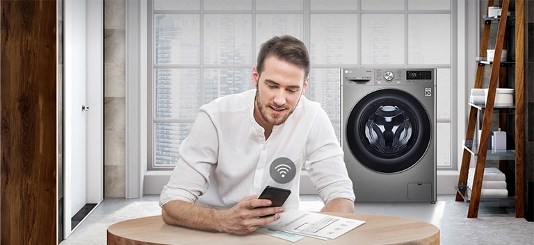 A man is monitoring the condition of the washing machine through a mobile phone app.