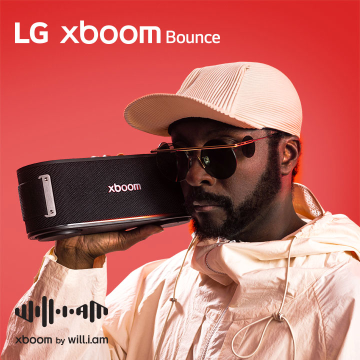 will.i.am in white outfit and sunglasses is holding xboom Bounce right next to his face.