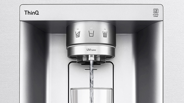 A video starts zoomed in on the water dispenser. The exterior of the refrigerator goes clear and now the interior of the door and mechanical parts of the dispenser nozzle can be seen. The video zooms in further to show the water droplets as they fall through the UVnano part of the nozzle which reduces the bacteria. The view zooms back out to see the exterior of the refrigerator again as water is being dispensed into a glass.