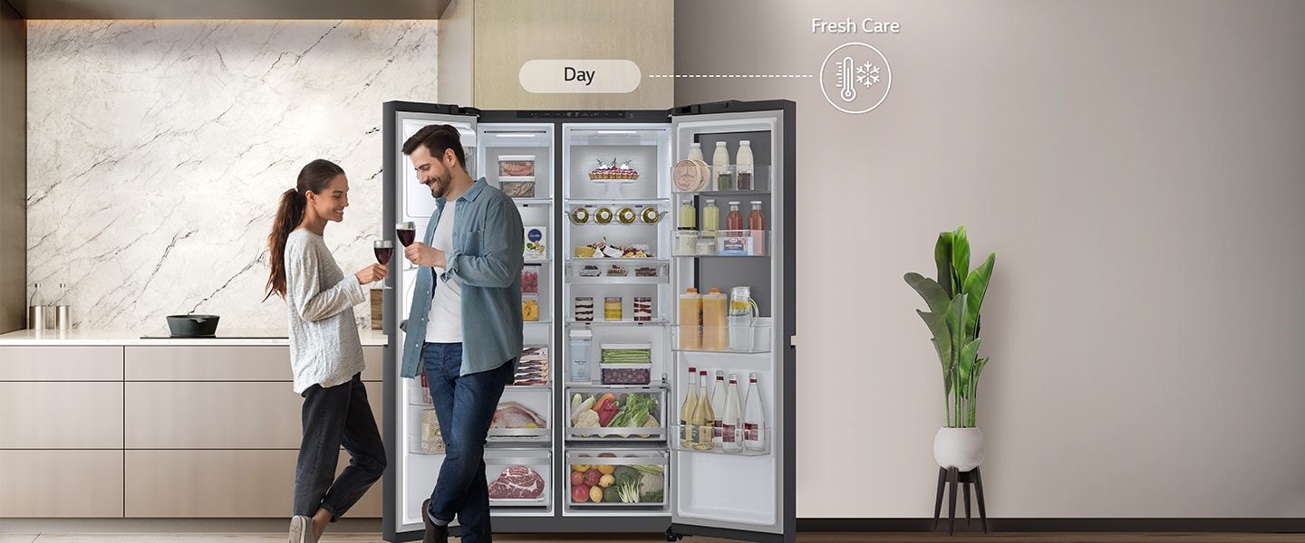 On the left side, The Fridge Freezer is open and the couple is standing near the Fridge Freezer the time seems to be evening on the right side with the energy-saving icon.
