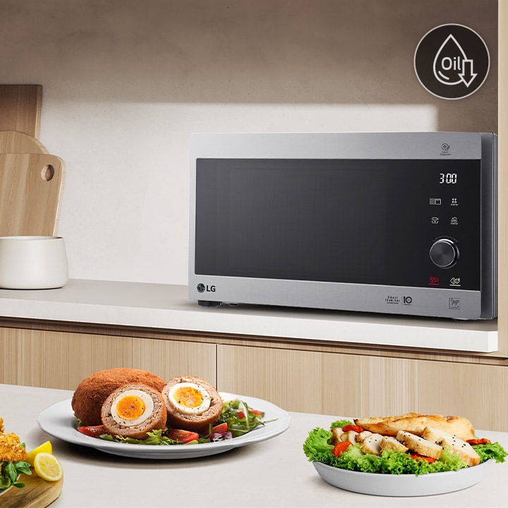 The image shows that a variety of foods are on the kitchen table, and roasted chicken is being cooked by neochef microwave oven.