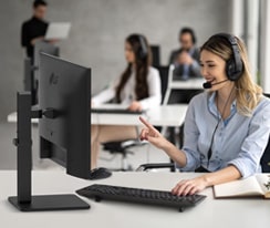 A woman wearing a headset is working while staring at a monitor.