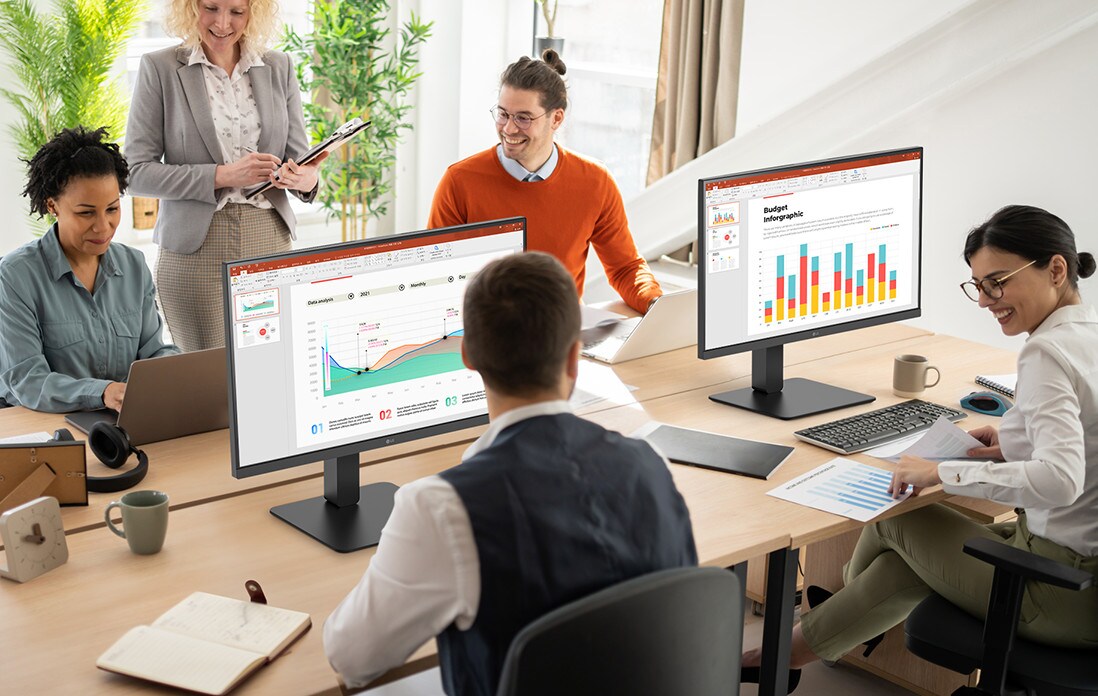 Employees sitting at office desks and having a conversation.	