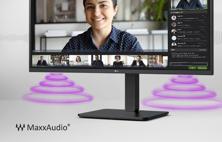 The monitor screen shows a video conference, while sound is coming from the speakers at the bottom of the monitor. In the bottom left corner, there is a MaxxAudio® logo.