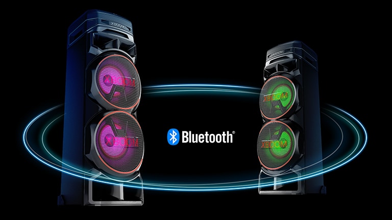 Two RNC7s facing each other at diagonal angles against a black background with a Bluetooth logo in between. One has purple light on the woofer, and the other has green light.